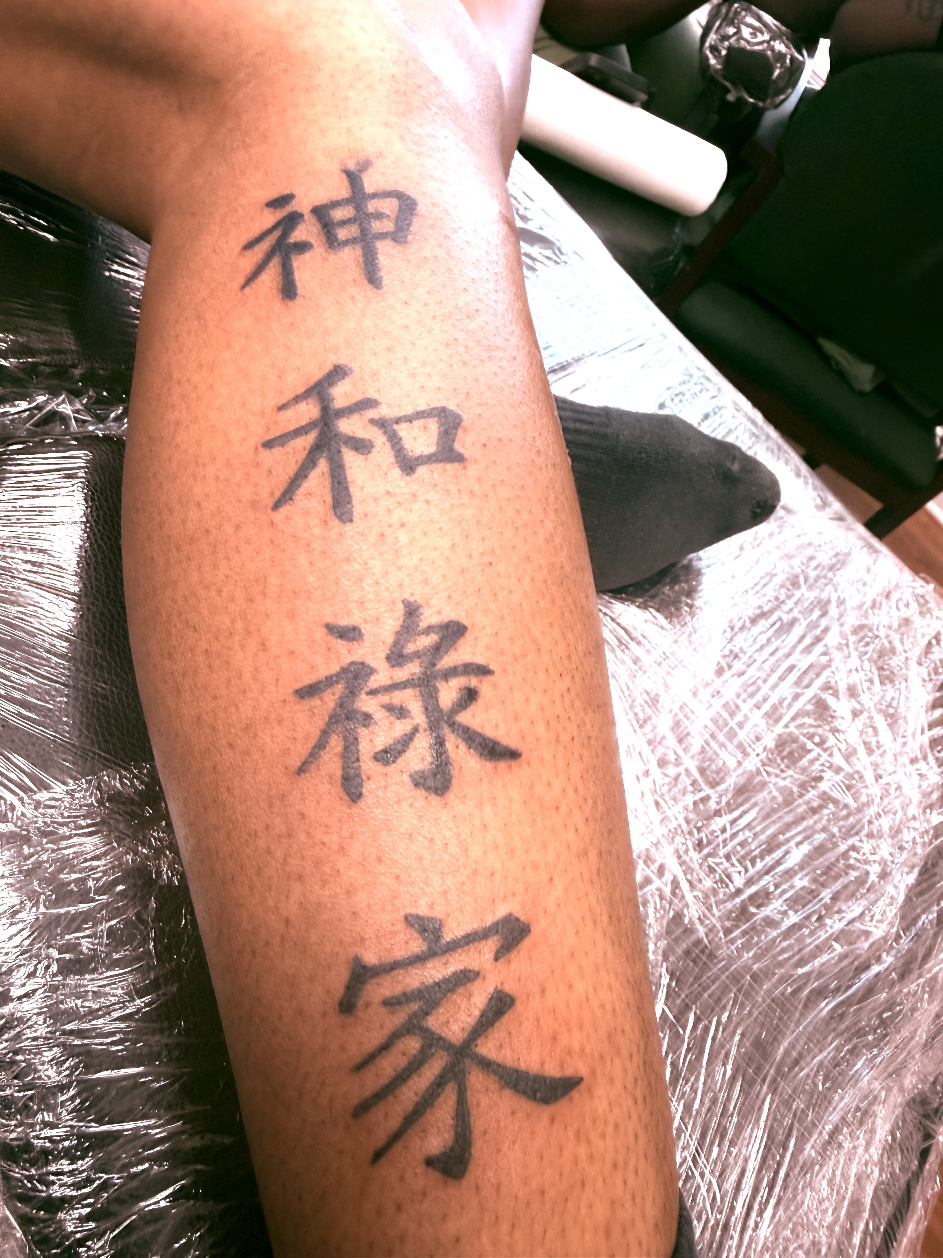 Bold black kanji character script tattoo on the forearm — four vertical characters